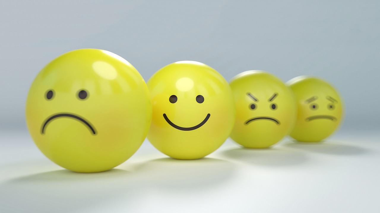 Some sad and grumpy 3D yellow stylised faces, and one happy one more in focus than the others